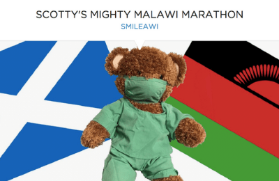 Photo of teddy bear wearing hospital scrubs and face mask in front of Scotland and Malawi flags